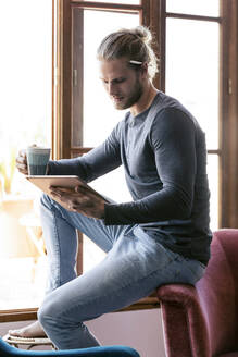 Junger Mann zu Hause, der ein digitales Tablet benutzt - JSRF00446