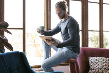 Young man at home using a digital tablet - JSRF00447