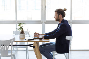 Geschäftsmann mit Laptop am Tisch in einem modernen Büro - JSRF00452