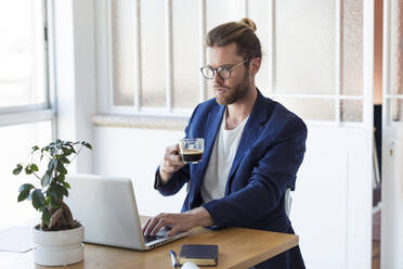 Geschäftsmann mit Laptop und einer Tasse Kaffee am Tisch - JSRF00457