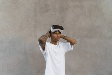 Tattooed young man with Virtual Reality Glasses looking up - MGIF00581