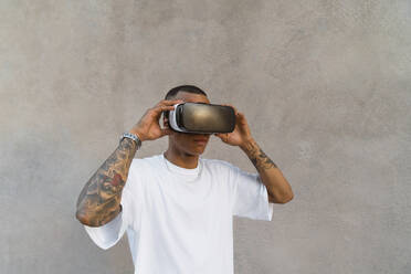 Tattooed young man using Virtual Reality Glasses looking up - MGIF00582