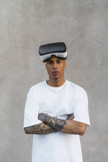 Porträt eines tätowierten jungen Mannes mit Virtual-Reality-Brille - MGIF00587