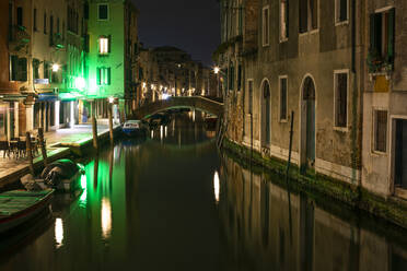Bridge over canal amidst buildings in Venice at night - LJF00460