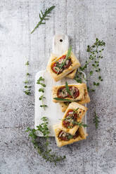 Directly above view of fresh puff pastry and herbs over cutting board on concrete - MYF02118