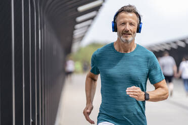 Sporty man wearing headphones and jogging - DIGF07492