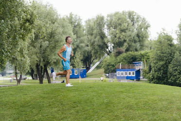 Sportlicher Mann beim Joggen in einem Park - DIGF07499