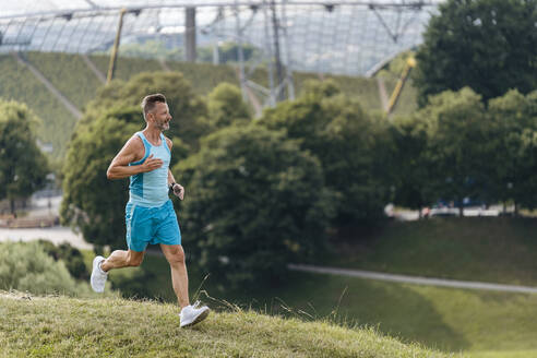 Sportlicher Mann beim Joggen in einem Park - DIGF07504