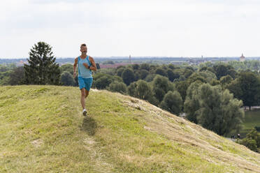 Sportlicher Mann beim Joggen in einem Park - DIGF07505