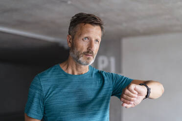 Portrait of a sporty man checking his smartwatch - DIGF07525