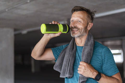 Sportlicher Mann mit Trinkflasche nach dem Training, lizenzfreies Stockfoto