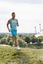 Sportlicher Mann beim Joggen in einem Park - DIGF07545