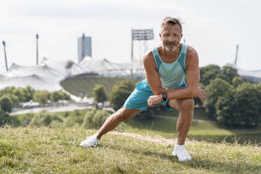 Sportlicher Mann beim Dehnen in einem Park - DIGF07546