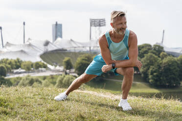 Sportlicher Mann beim Dehnen in einem Park - DIGF07547