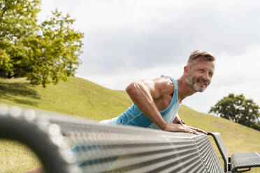 Sportlicher Mann beim Dehnen in einem Park - DIGF07549