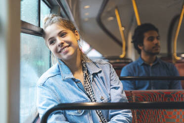 Porträt einer glücklichen jungen Frau, die mit dem Bus fährt, London, UK - WPEF01579