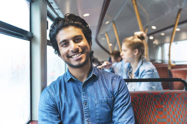 Porträt eines glücklichen jungen Mannes, der mit dem Bus fährt, London, UK - WPEF01586