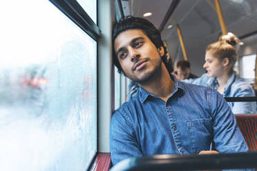 Portrait of daydreaming young man travelling by bus, London, UK - WPEF01587