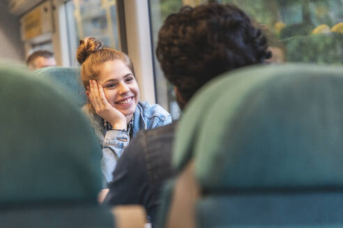 Porträt einer glücklichen jungen Frau, die mit ihrem Freund im Zug reist, London, UK - WPEF01606