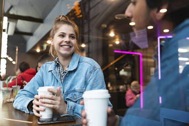 Porträt einer lächelnden jungen Frau in einem Café, die einen jungen Mann ansieht - WPEF01608