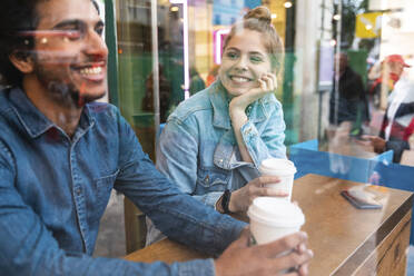 Portrait of smiling young woman in a coffee shop looking at young man - WPEF01613
