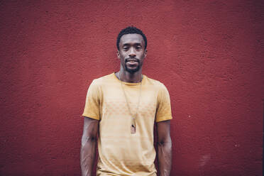 Portrait of bearded young man in front of red wall - OCMF00477