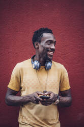 Porträt eines lächelnden Mannes mit Kopfhörern und Smartphone - OCMF00479
