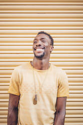 Porträt eines lachenden Mannes mit gelbem T-Shirt und Halskette - OCMF00484