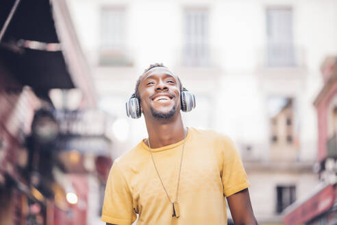 Porträt eines glücklichen Mannes, der mit Kopfhörern Musik hört - OCMF00487