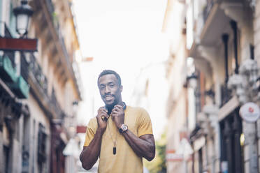 Portrait of smiling man with headphones in the city - OCMF00493