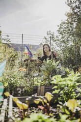 Junge Frau fotografiert mit ihrem Smartphone in einem städtischen Garten - VGPF00050