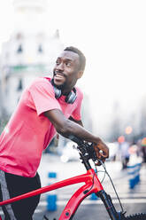 Happy young man with e bike in the city - OCMF00495