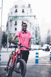 Portrait of young man with e bike in the city - OCMF00501