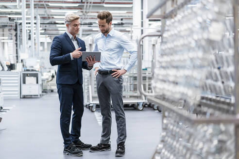 Zwei Geschäftsleute mit Tablet im Gespräch in einer modernen Fabrik - DIGF07560