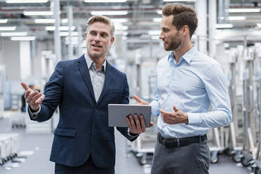 Two businessmen with tablet talking in a modern factory - DIGF07561