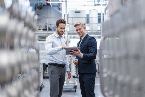 Zwei Geschäftsleute mit Tablet im Gespräch in einer modernen Fabrik - DIGF07562