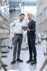 Two businessmen with tablet talking in a modern factory - DIGF07563