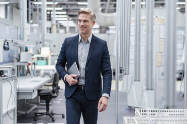 Confident businessman with tablet in a modern factory - DIGF07572