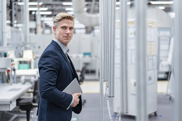 Confident businessman with tablet in a modern factory - DIGF07573