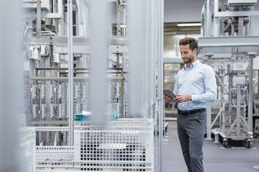 Businessman using tablet in a modern factory - DIGF07576