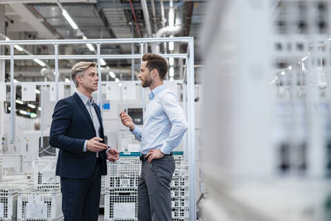 Zwei Geschäftsleute im Gespräch in einer modernen Fabrik, lizenzfreies Stockfoto