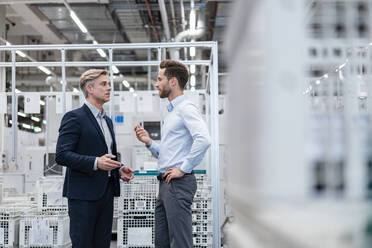 Zwei Geschäftsleute im Gespräch in einer modernen Fabrik - DIGF07581