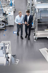 Two businessmen with clipboard talking in a factory - DIGF07591