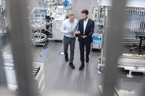 Zwei Geschäftsleute mit Klemmbrett im Gespräch in einer Fabrik - DIGF07592