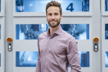 Portrait of a confident businessman in front of a machine in a factory - DIGF07611