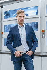 Portrait of a confident businessman in front of a machine in a factory - DIGF07614