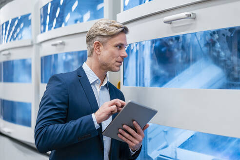 Geschäftsmann mit Tablet an einer Maschine in einer Fabrik - DIGF07616