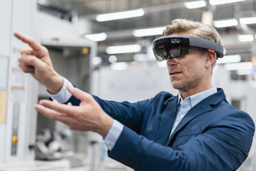 Businessman wearing AR glasses in a modern factory - DIGF07625