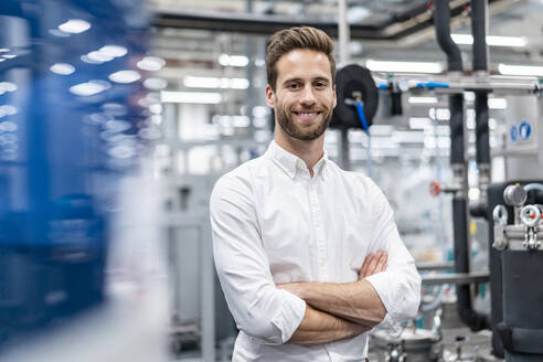 Porträt eines lächelnden Geschäftsmannes in einer modernen Fabrik - DIGF07633