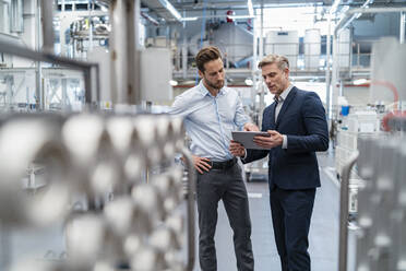 Zwei Geschäftsleute mit Tablet im Gespräch in einer modernen Fabrik - DIGF07646